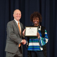 Doctor Potteiger posing for a photo with an award recipient in a blue and green striped top